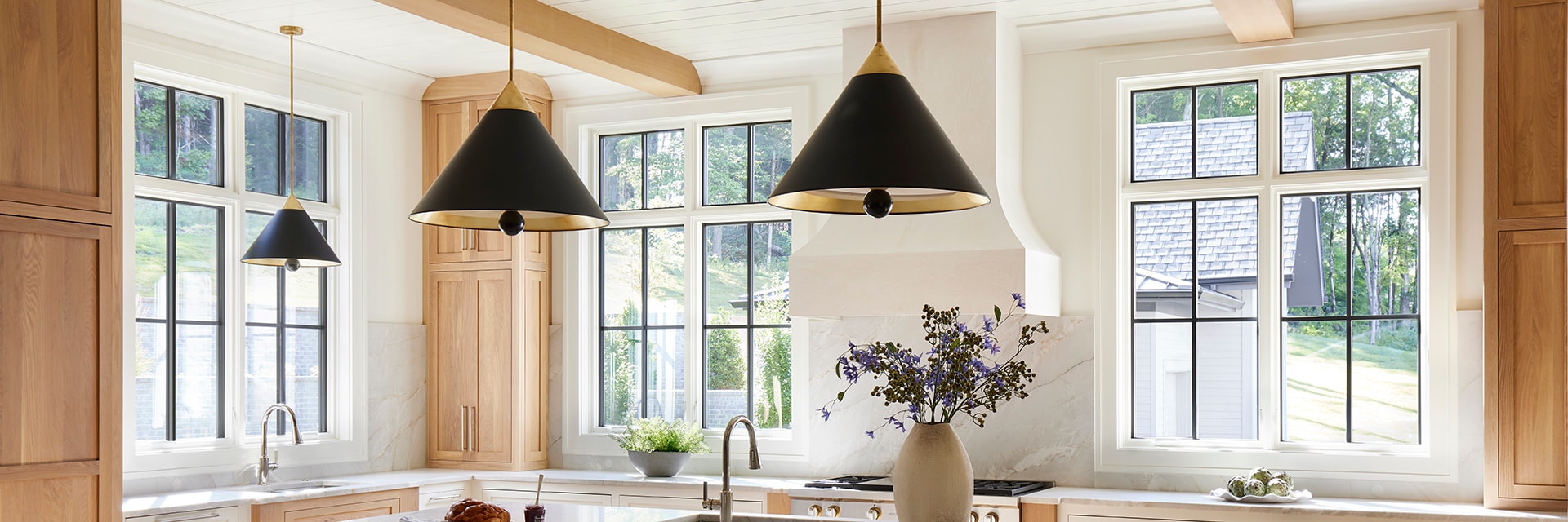 Three black lights hang over a large island with groupings of black casement windows behind.