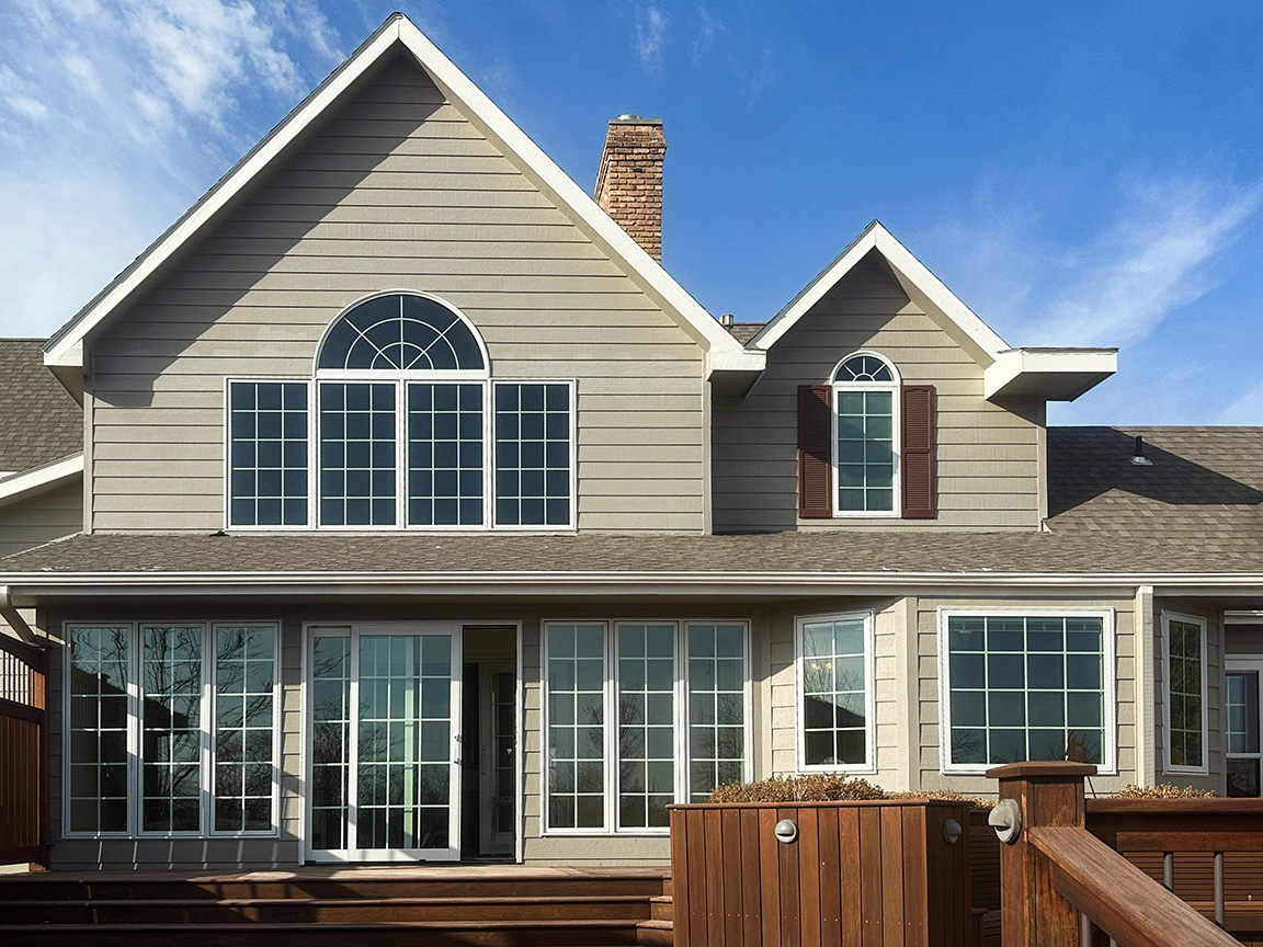 A modern house exterior featuring large replacement windows and a wooden deck.