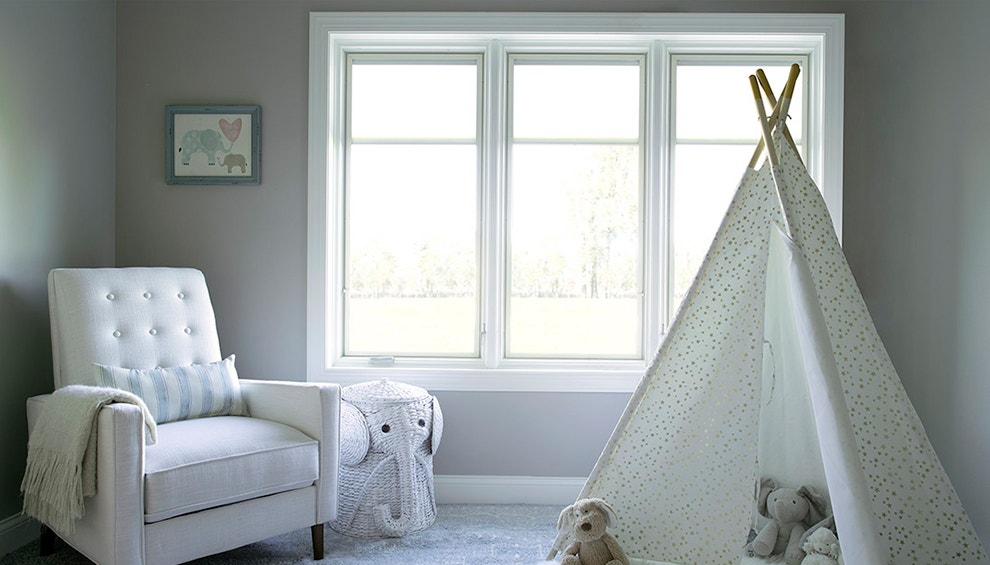 A play tent sits in front of three casement windows in a child's bedroom