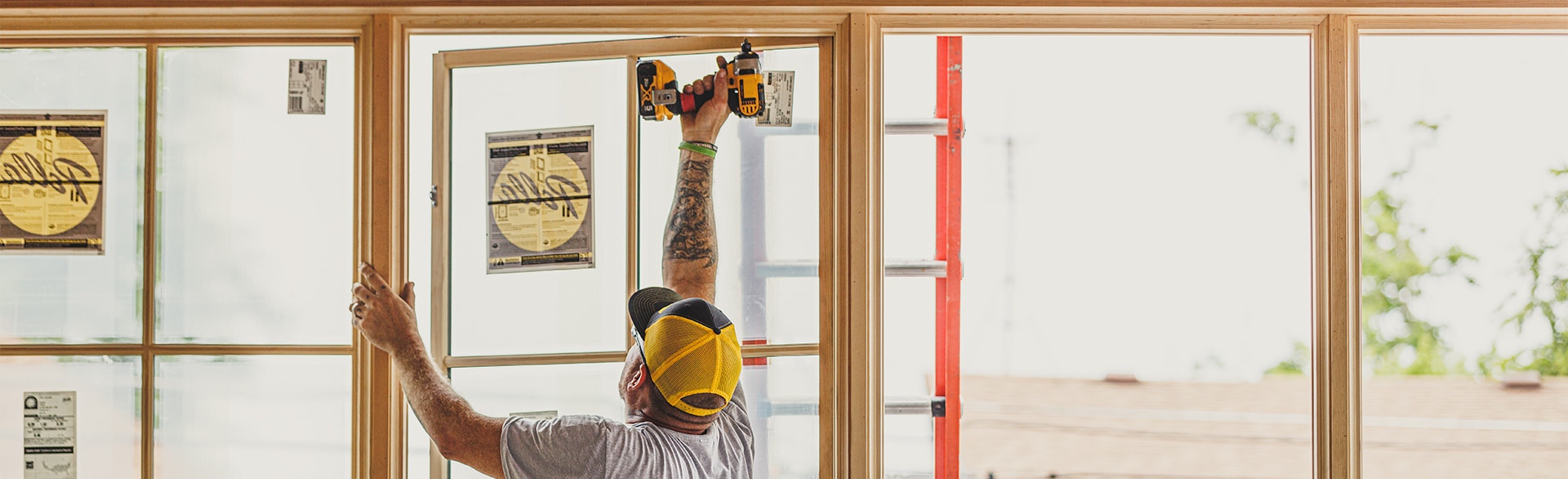 A Pella contractor is using a drill to install a wood casement window.