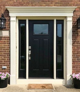 Black front door with matching sidelights on each side surrounded by elegant white trim