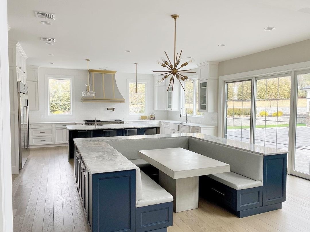 White windows and doors surround a kitchen and dining room space with blue cabinetry.