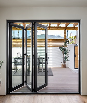 four panels of a bifold patio door open to the left of the opening as seen from the exterior
