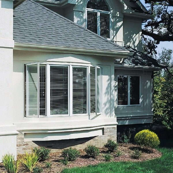 Exterior of home with a white bow window with casement windows and blinds