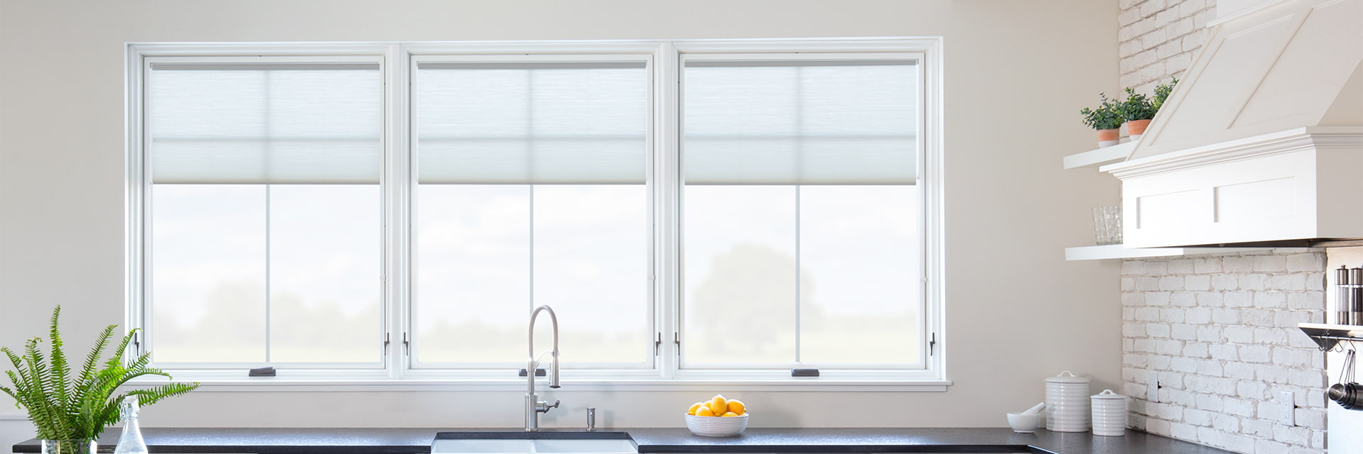 three white casement windows sit over a kitchen counter behind a large island.