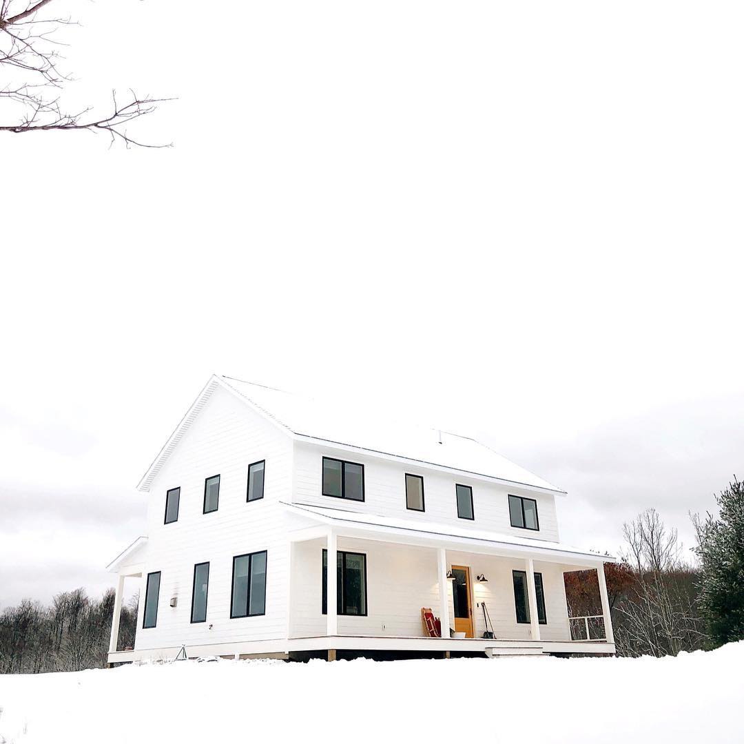 White farmhouse with black casement windows on snowy day