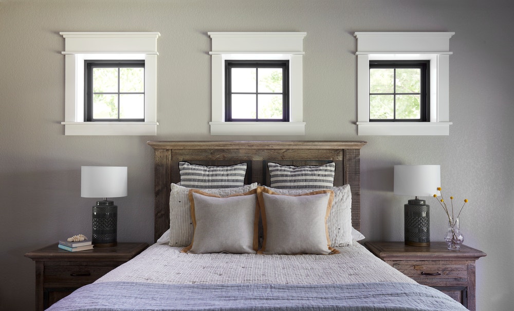 Three square black windows with white trim above bed