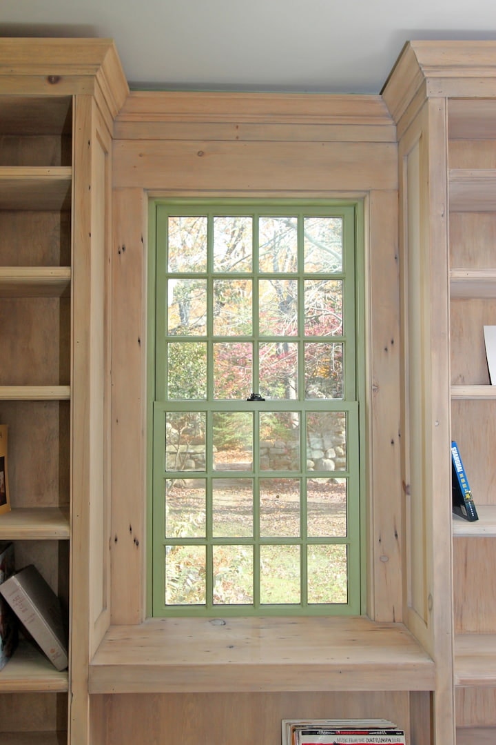 Green Window Acts As Art For Farmhouse Office green double-hung window surrounded by natural wood bookcase on either side