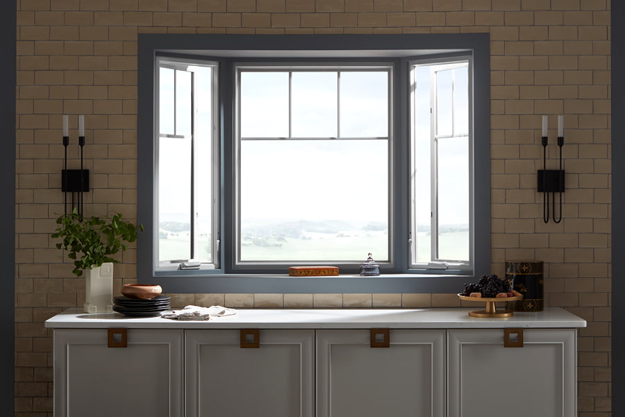 Gray bay windows in kitchen above the counter with black candle sconces