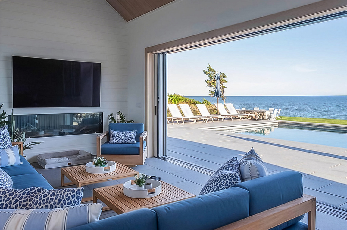 Pool house lounge featuring blue seating and ocean view through sliding glass doors