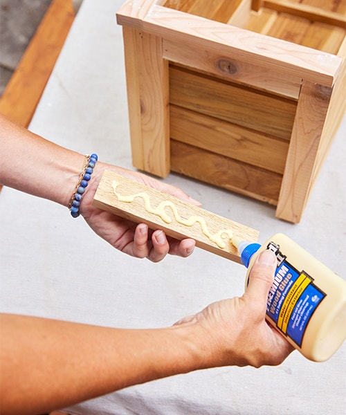 Applying wood glue to a cedar board that will be attached to a wood window box.