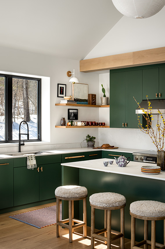 A modern kitchen with green cabinets and featuring fiberglass windows.
