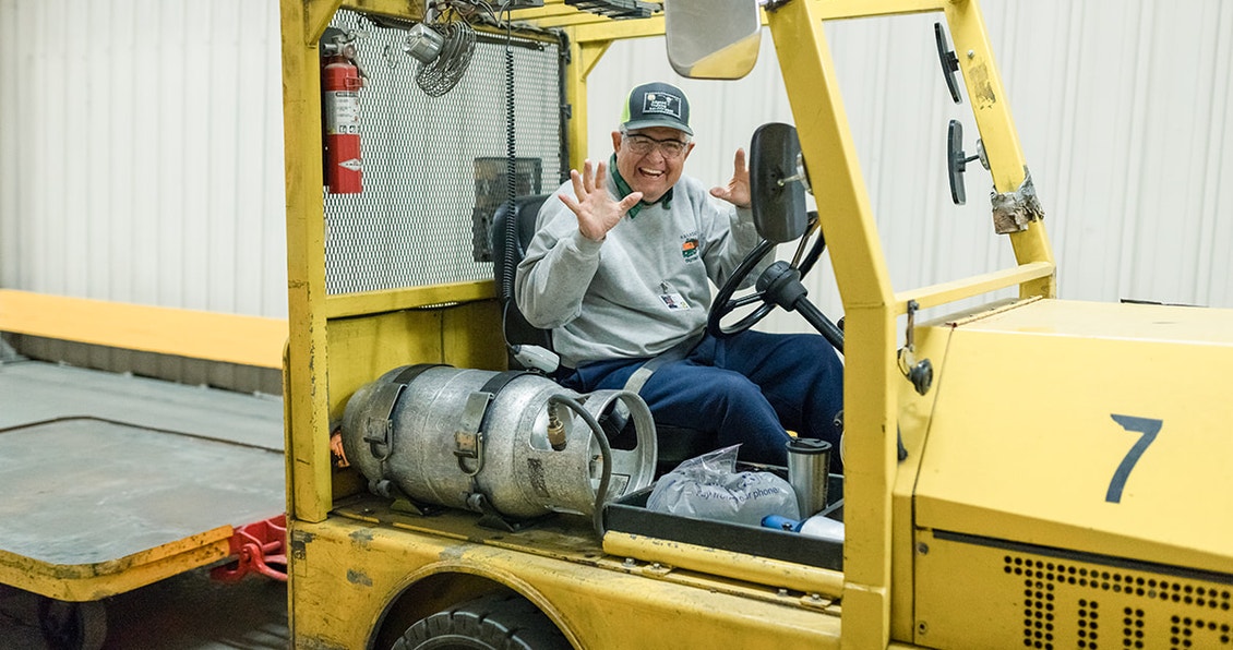 pella employee driving a fork truck saying hi