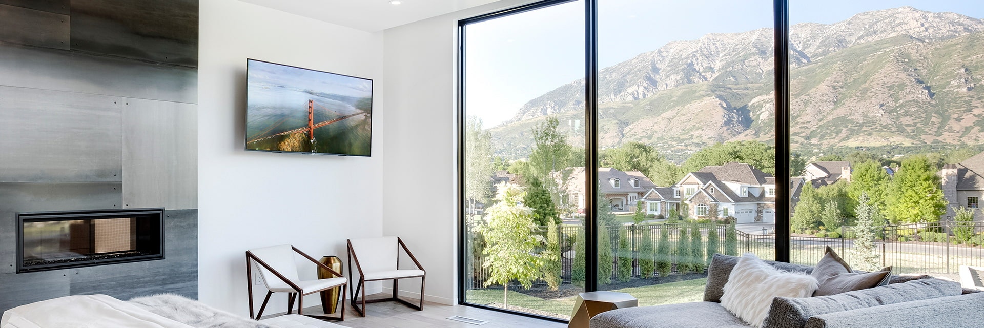 floor-to-ceiling windows on a contemporary living room wall bring the mountain view into the home.
