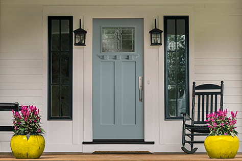 a light blue craftsman light entry door frames the front deck