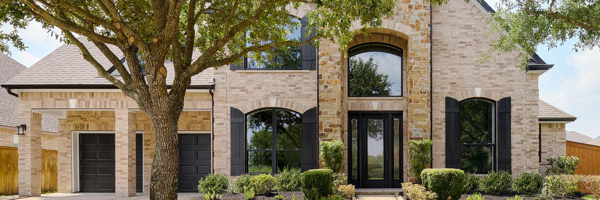 Brick house with black shutters and arched windows in Houston.