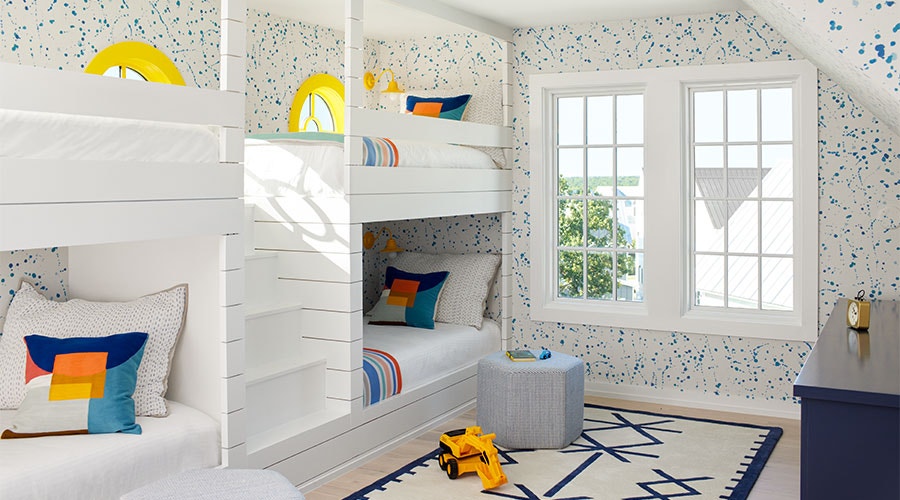 a kids bunk room with colorful blue and white wallpaper and two white windows on the far wall