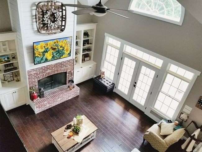 Interior living space with fireplace, white French doors, half circle window close to ceiling, double-hung windows and transoms.
