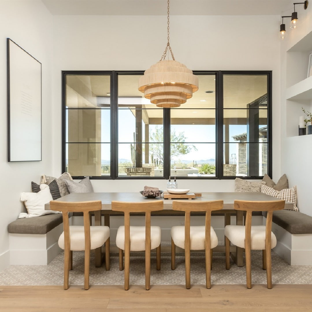A modern dining room features black windows with horizontal grilles behind the table.