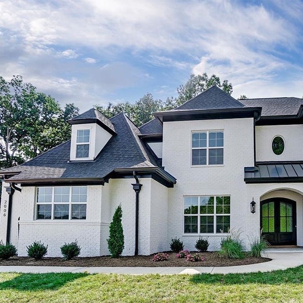 white home with a black roof and hipped dormer windows