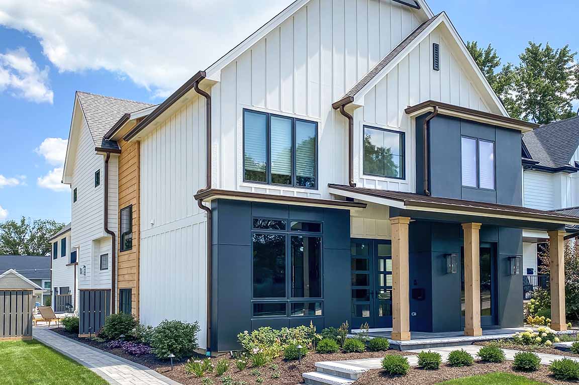 Modern farmhouse exterior featuring black-framed windows, mixed siding, and contemporary rooflines.