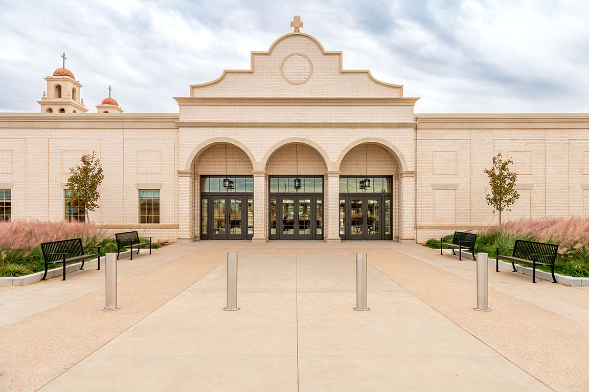 Elegant church exterior with arched entrance, light brick facade, and landscaped walkway