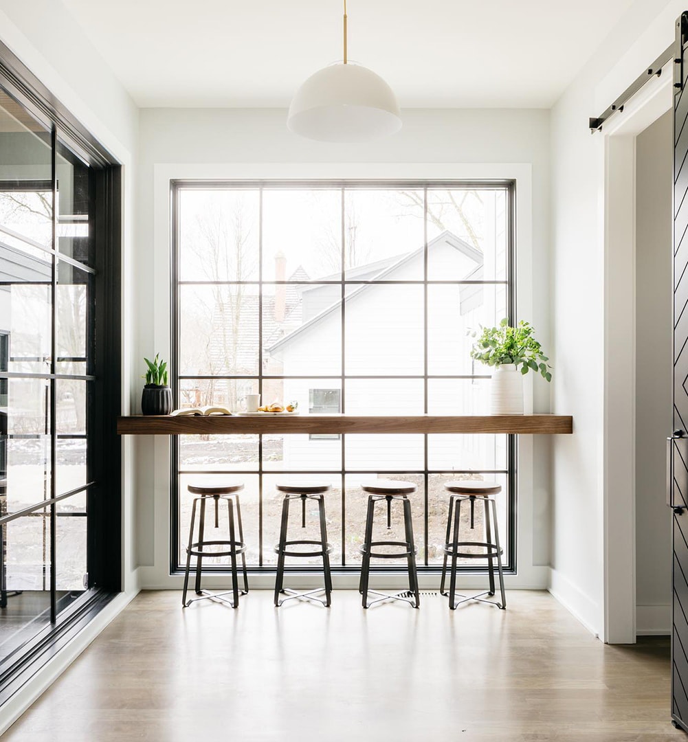 A floor-to-ceiling picture window with grilles behind a long countertop adds to modern kitchen.