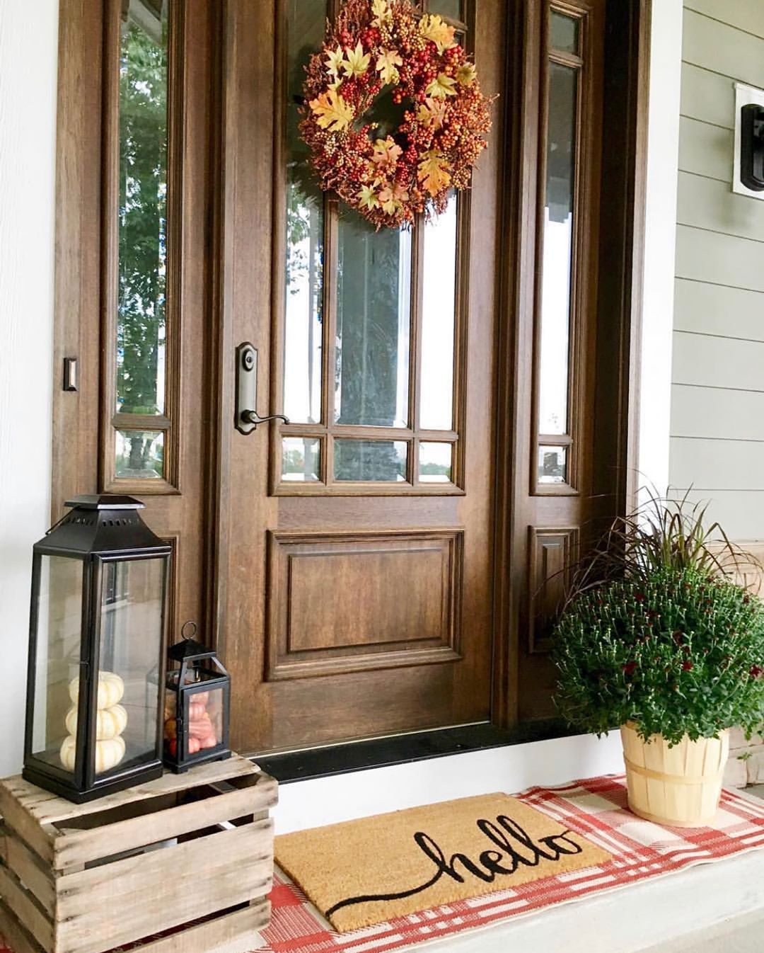 Wood stained front door with glass and matching sidelights surrounded by seasonal décor
