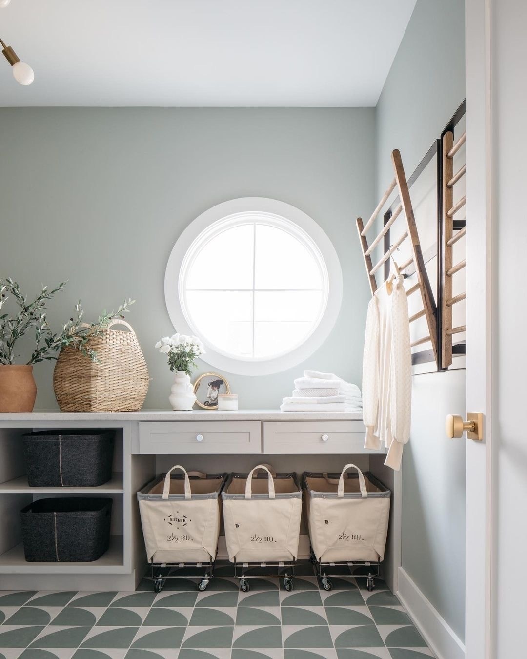 A white laundry room window in the shape of a circle brings natural light in.