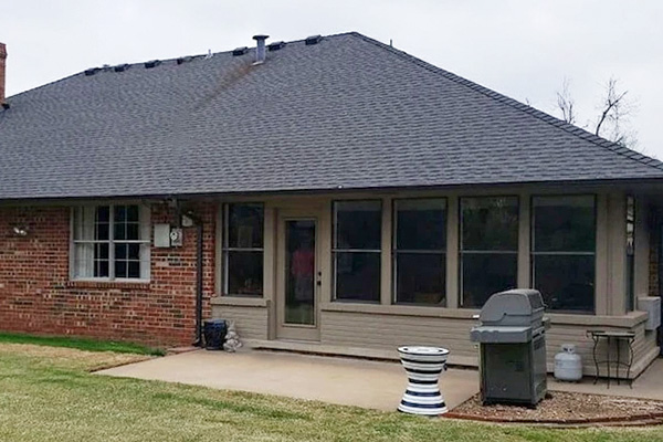 brick single-story home with outdated windows and a patio door