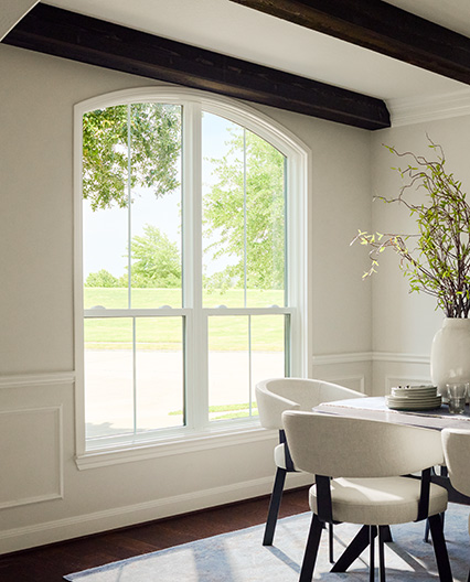Arched window in a Houston dining room with white walls and dark ceiling beams.