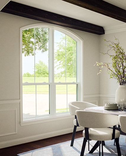 Arched window in a Houston dining room with white walls and dark ceiling beams.