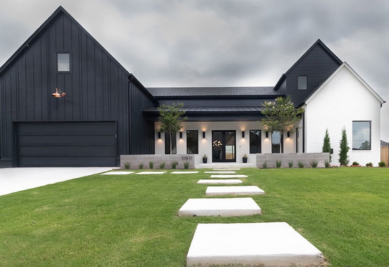 A new home in Tulsa with both black and white siding, contemporary stepping stones, and black front doors and windows