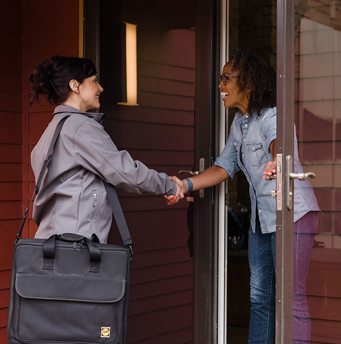 Two people shake hands at a doorway with red siding in Austin.