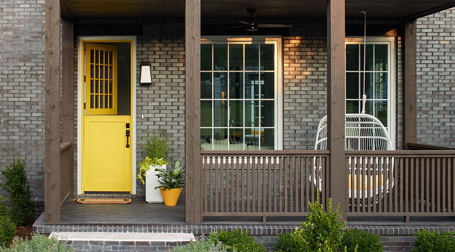 yellow dutch door front porch brick home potted plants