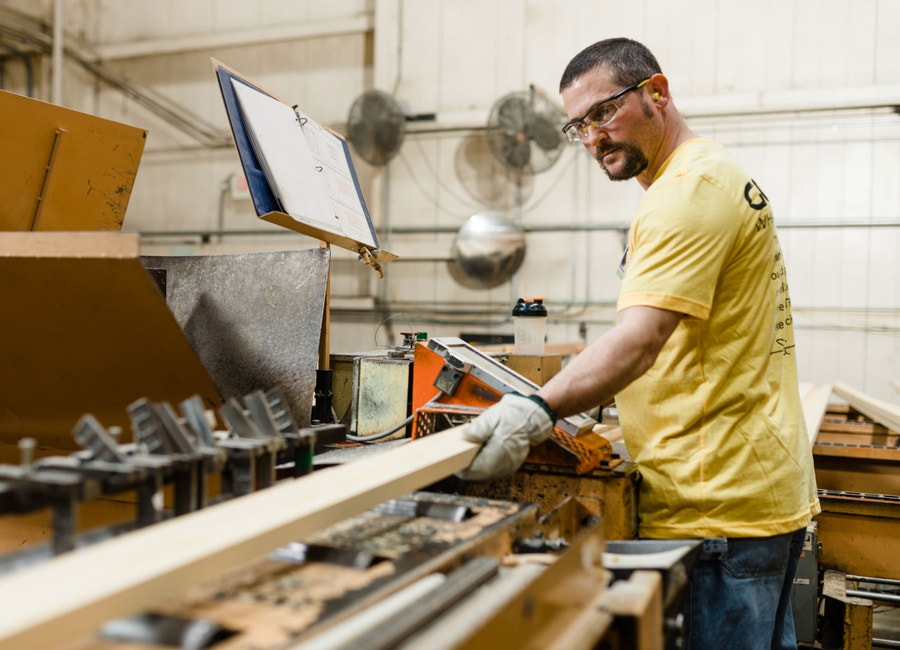 a pella factory working monitoring a piece of raw wood