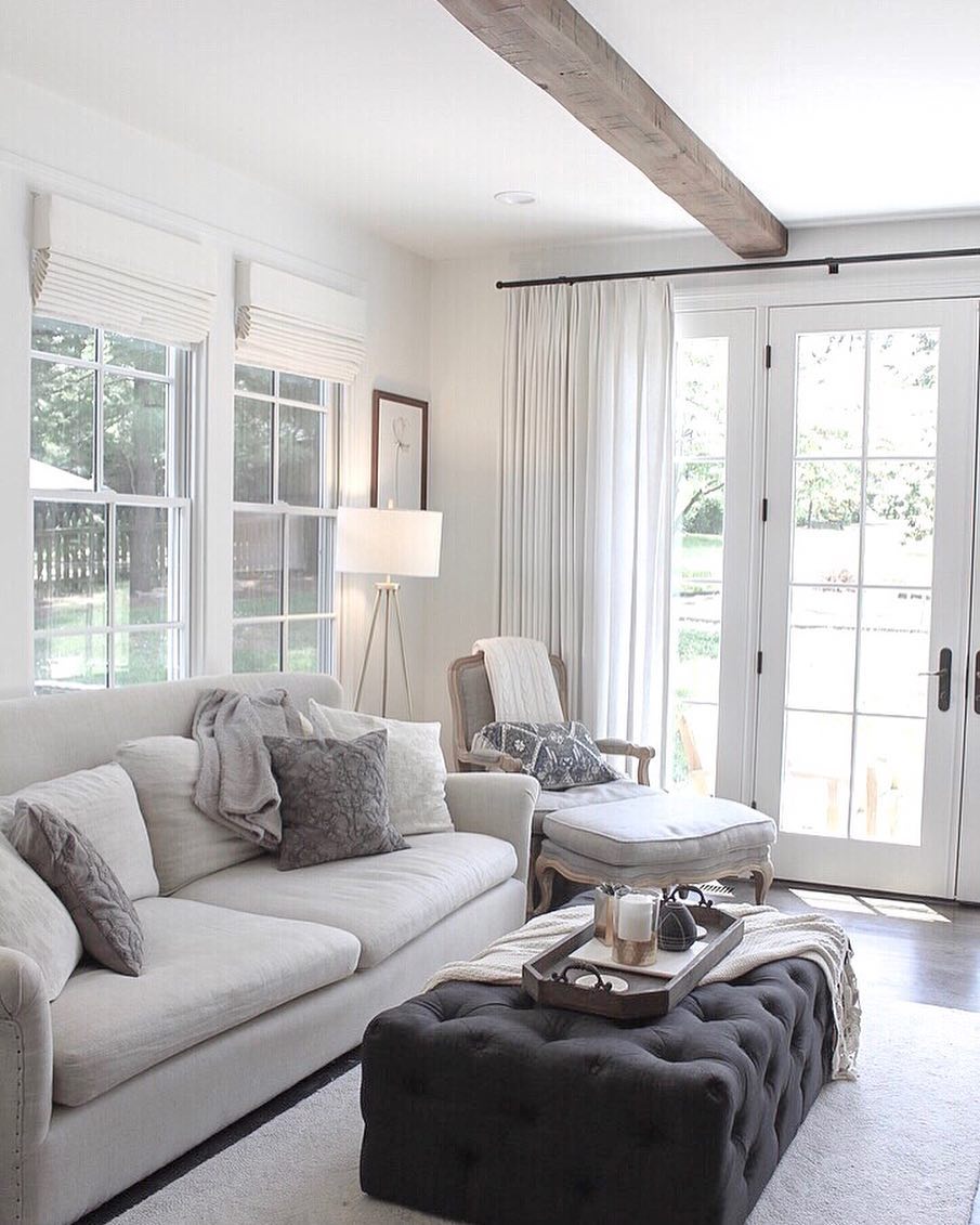white on white living room couch, chair, and gray ottoman next to set of white french doors
