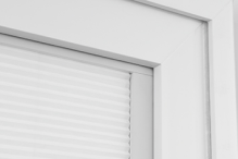 The corner of a white Pella 350 Series vinyl window featuring the removal of a raised weld.