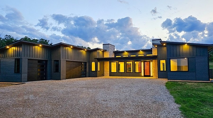 Modern new construction home with lights shining from large windows at dusk. 