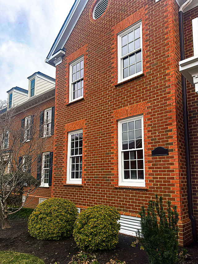 Traditional brick home exterior with white framed double‑hung windows and classic architectural detailing.