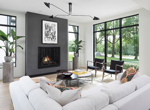 Contemporary living room with black windows, a white sectional, fireplace, and two contemporary chairs.