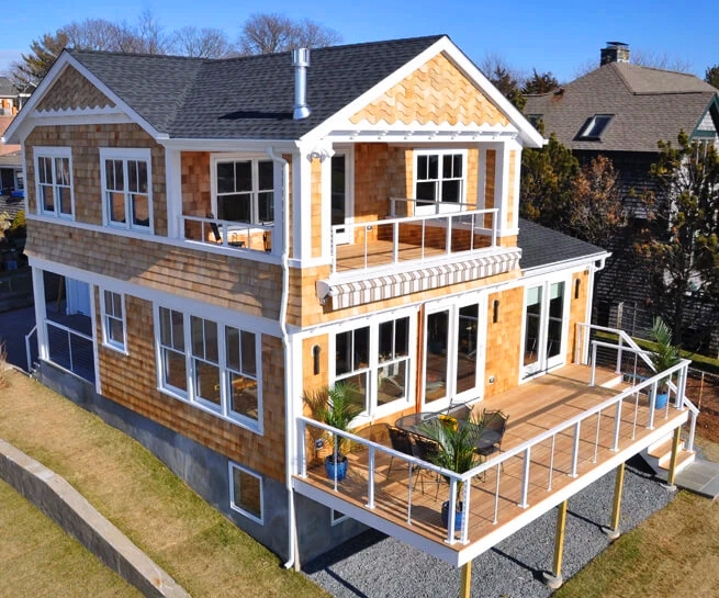  Exterior view of Barrington Cape Cod home with newly installed wood double-hung windows and sliding door.