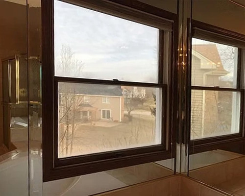 Two old wood double-hung windows in an out-of-date bathroom.