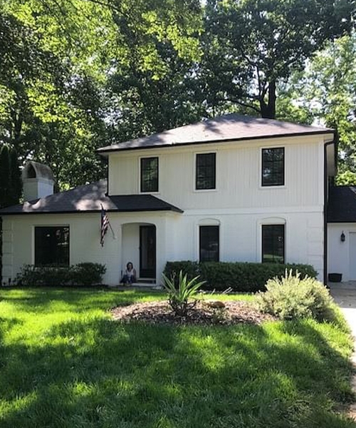 a white home with black Pella wood windows adds drama to the curb appeal of the home