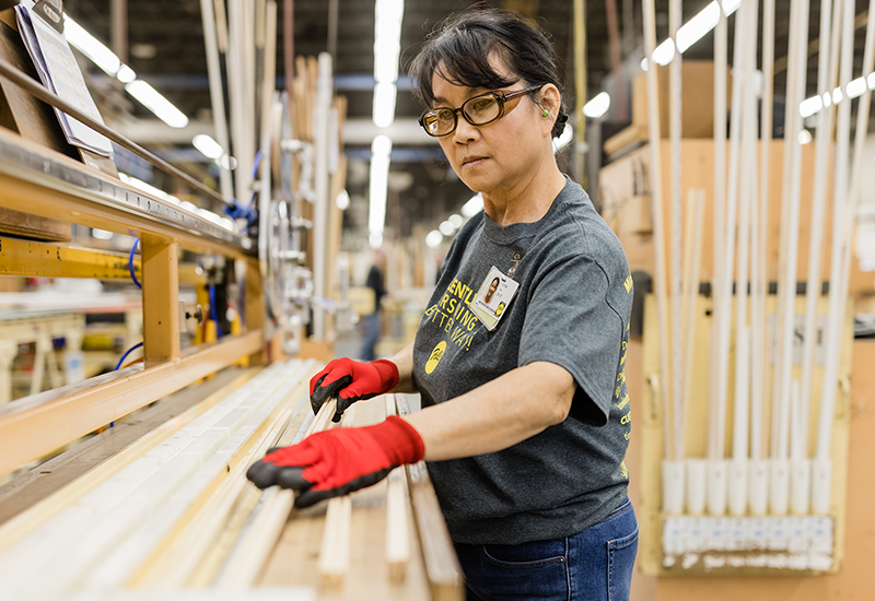 a woman working in the Pella manufacturing plant quality-checking wood materials