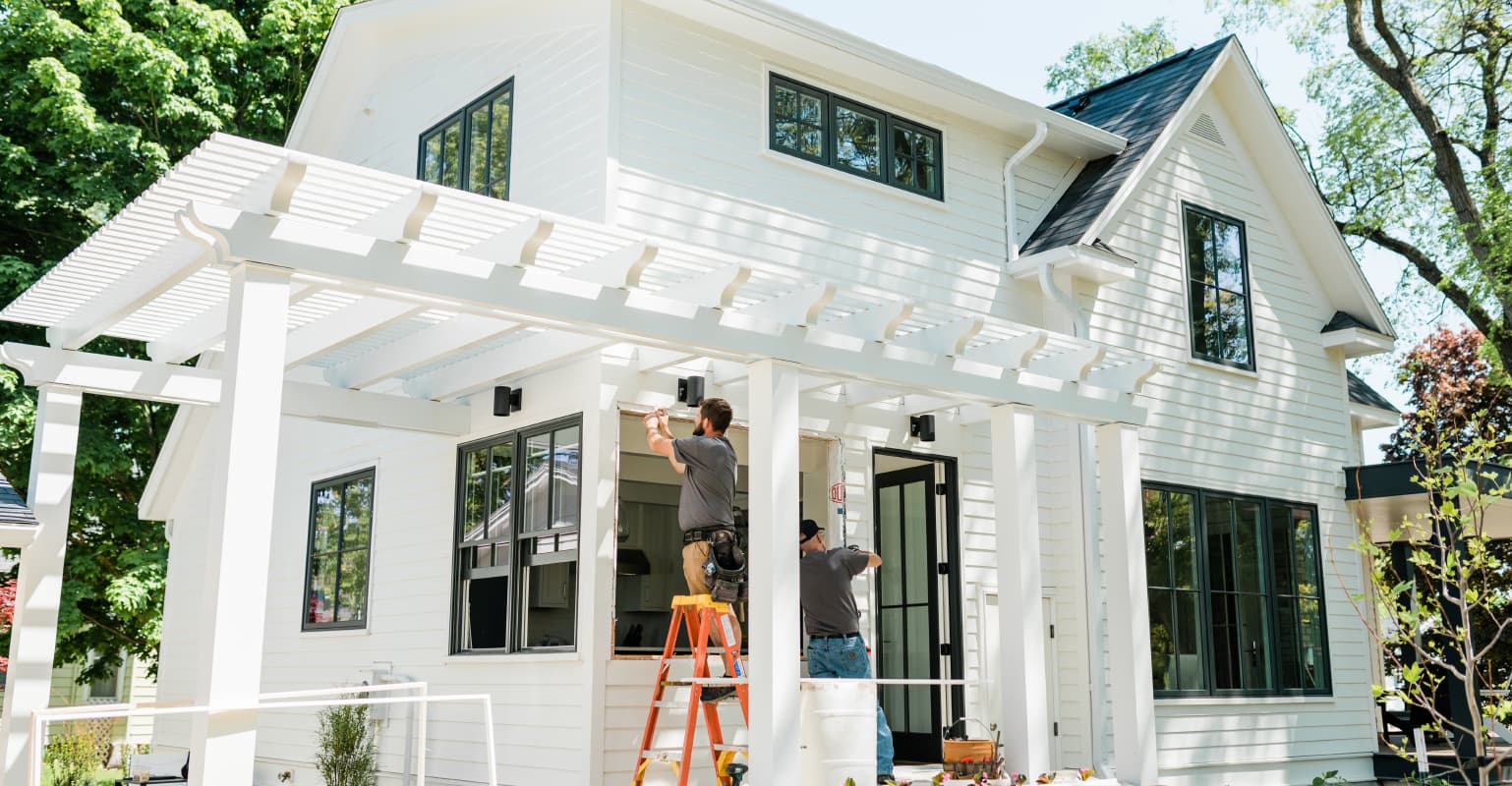 farmhouse-style white home is getting new windows as two contractors work to install them
