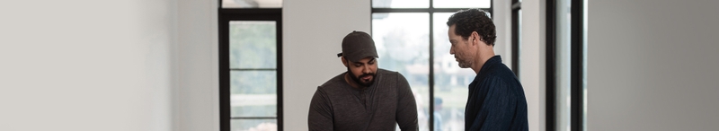 two man in a room with white walls discussing a project