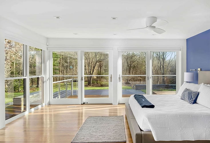 A renovated master bedroom in the Boston area with floor-to-ceiling windows and hinged doors.