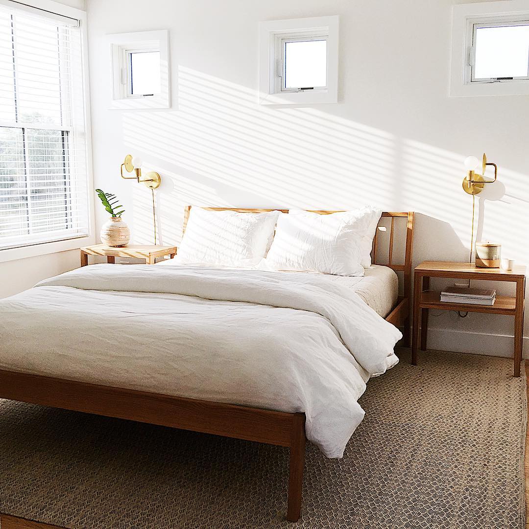 light streaming into white bedroom through large double-hung window with three square windows above bed
