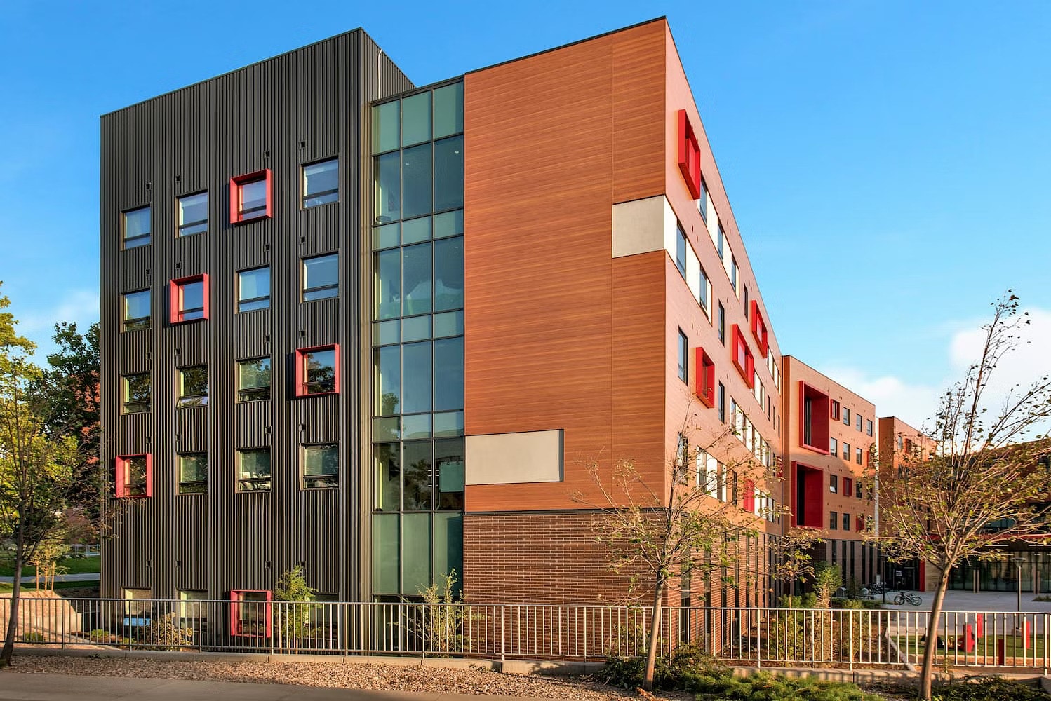 An updated University of Utah student housing building with orange and black siding and black windows